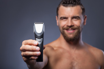 Cheerful bearded guy is showing new shaver