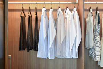 row of white shirts hanging in wooden wardrobe