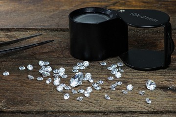 geschliffene Diamanten mit Einschlaglupe auf rustikalem Holzhintergrund