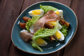 Salad with fig fruits, ham and eggs. Above view, studio shot