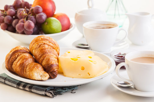 Croissants with cheese, fruits and coffee