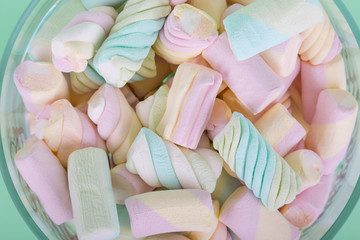 marshmallow candies of different colors in the glass on the background of turquoise. top view. entertainment for children in celebration.