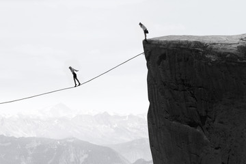 Businesswoman walking on the rope over the gap