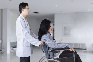 Obraz premium Doctor pushing patient on wheelchair