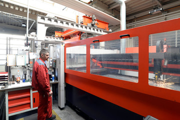 Mann bedient Laserschneidmaschine in der Industrie // 
Man uses laser cutting machine in the...