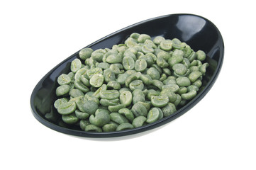 Black bowl with green coffee beans on the white