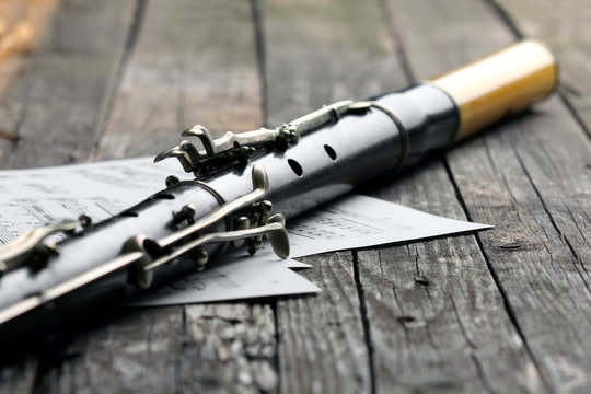 Old black flute and music notes on rusty wooden table