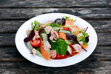 Tuna salad with Spinach, rocket, red ruby chard, tomatoes, cucumbers, white cheese, carrot, red onion, croutons on old blue stone background