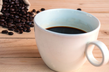 Coffee beans sack and coffee cup over wooden background