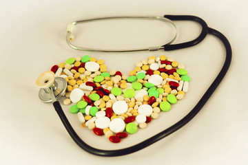 Tablets, medicines arranged in the form of heart with a stethoscope - obrazy, fototapety, plakaty
