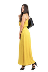 Beautiful fashion model in yellow jumpsuit walking with bag over the shoulder isolated