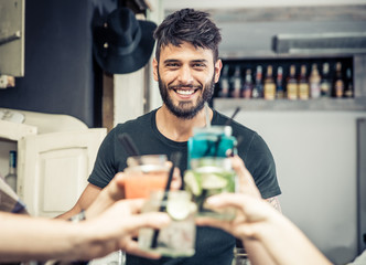Fototapeta na wymiar Smiling bartender with cocktails toast