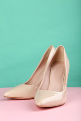 Pair of beige women's high-heeled shoes on pink background