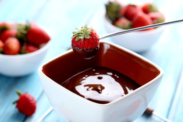 Chocolate fondue with fresh berries on a blue wooden table
