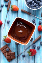 Chocolate fondue with fresh berries on a blue wooden table