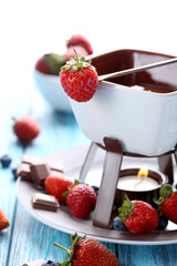 Chocolate fondue with fresh berries on a blue wooden table