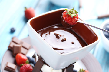 Chocolate fondue with fresh berries on a blue wooden table