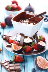 Chocolate fondue with fresh berries on a blue wooden table