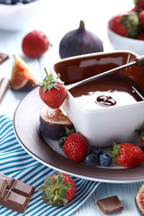 Chocolate fondue with fresh berries on a blue wooden table