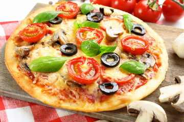 Tasty pizza with vegetables and basil on table close up