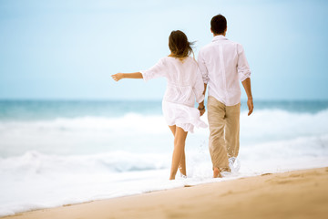 happy romantic young couple walking at the beach