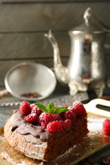 Piece of cake with Chocolate Glaze and raspberries on tray on wooden background