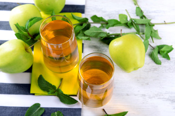 Glasses of apple juice with fruits and fresh mint on table close up