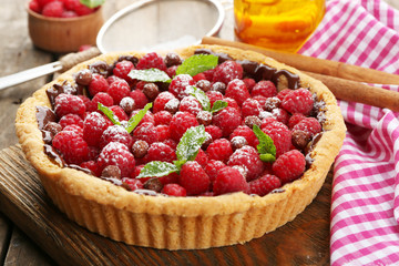 Tart with fresh raspberries, on wooden background