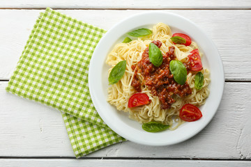 Spaghetti Bolognese on white plate, on color wooden background