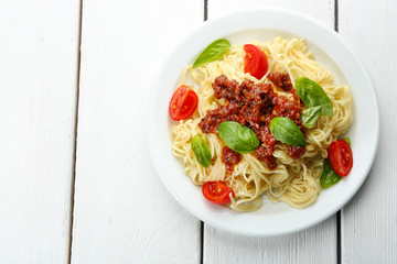 Spaghetti Bolognese on white plate, on color wooden background
