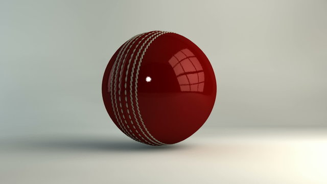 A shiny reflective red leather cricket ball spinning around on an isolated white background