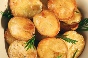 Delicious baked potato with rosemary in bowl close up