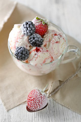 Delicious ice cream with fresh frozen berries, on color wooden background