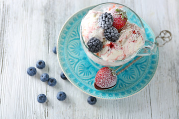 Delicious ice cream with fresh frozen berries, on color wooden background