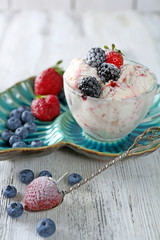 Delicious ice cream with fresh frozen berries, on color wooden background