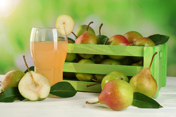 Glass of juice with fresh pears on wooden table on blurred background