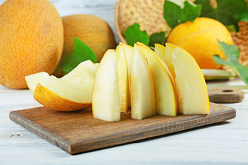 Slices of ripe melons with green leaves on table close up