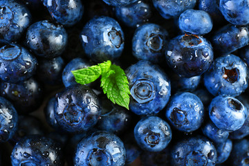 Tasty ripe blueberries with green leaves close up
