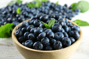 Tasty ripe blueberries with mint in bowl on table close up