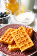 Sweet homemade waffles on plate, on color wooden background