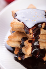 Christmas cookies with chocolate syrup and sugar balls on a white plate.