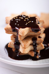 Christmas cookies with chocolate syrup and sugar balls on a white plate.