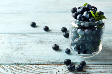 Fresh blueberries in jar on wooden table close up