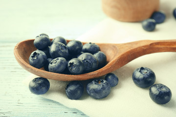 Fresh blueberries in spoon on wooden table close up