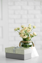 Fototapeta premium Big beautiful gift box with bouquet of flowers on the table in front of brick wall, close up