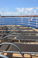 Fototapeta premium Pool chairs on top deck of cruise ship at sea