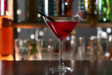 Red alcohol cocktail with sugared cherry on the bar counter, close up