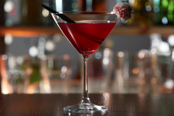 Red alcohol cocktail with sugared cherry on the bar counter, close up