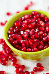 pomegranate seeds in a bowl on wooden surface