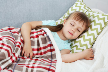 Little girl sleeping on sofa in room